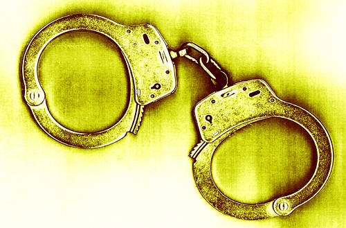handcuffs against yellow, getty images thia0004473 (RF)